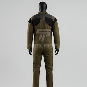 May include: A two-piece olive green jumpsuit with black and gray accents on the shoulders and upper back. The jumpsuit has a high collar and multiple pockets. The text "TASTIC PROPS" is visible on the lower portion of the image.