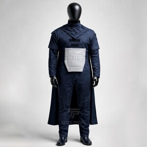 May include: A navy blue costume displayed on a mannequin. The costume includes a hooded top, a cape, and pants. A light gray padded panel is on the chest. The costume is made of a textured fabric. The mannequin is black.