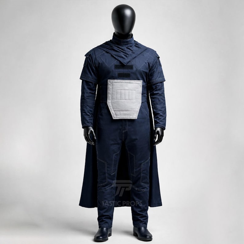 May include: A navy blue costume displayed on a mannequin. The costume includes a hooded top, a cape, and pants. A light gray padded panel is on the chest. The costume is made of a textured fabric. The mannequin is black.