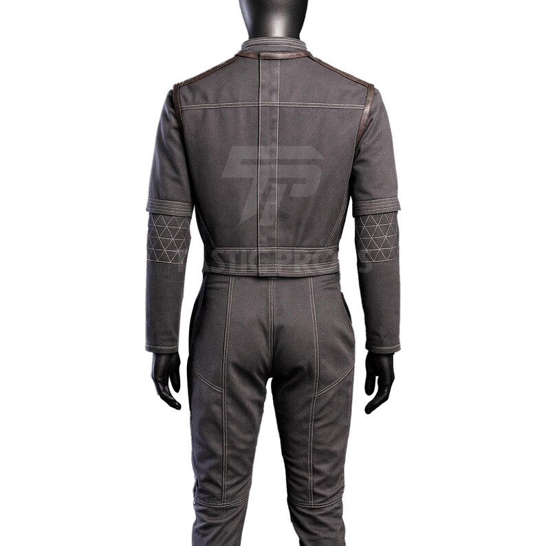 May include: A gray jumpsuit with a matching jacket. The jacket has brown trim on the shoulders and a geometric pattern on the sleeves. The jumpsuit has visible stitching and a belt at the waist.