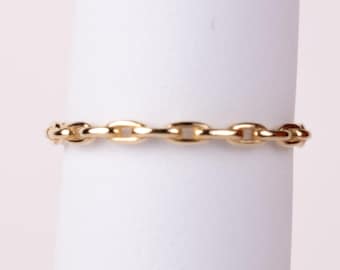 Könnte beinhalten: Ein goldener Ring mit einem durchgehenden Kettenglied-Design. Das Band besteht aus kleinen, gleichmäßigen, polierten ovalen Gliedern, die in einer Reihe verbunden sind und ein flexibles Aussehen mit einem hellen, reflektierenden Metallfinish erzeugen.