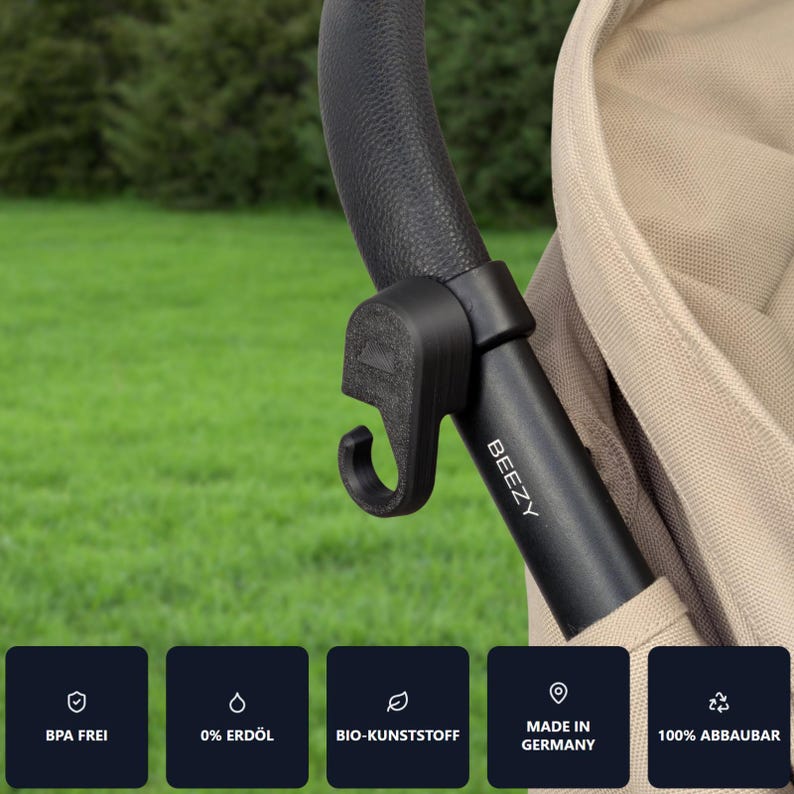 May include: A black stroller hook attached to a black handle. The hook is labeled "BEEZY" and is made in Germany. The hook is BPA free, made of bio-plastic, and 100% biodegradable.