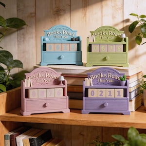 Puede incluir: Cuatro organizadores de madera en colores pastel con tem&aacute;tica de libros. Cada uno tiene un caj&oacute;n y una estanter&iacute;a con el texto "Books Read This Year". Las estanter&iacute;as contienen bloques de madera con n&uacute;meros. Los organizadores son azules, verdes, rosas y morados.