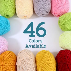 Op de afbeelding: Een verzameling van 46 garenkleuren, waaronder tinten groen, geel, roze en blauw, gerangschikt rond de tekst "46 kleuren beschikbaar". Het garen is strak opgerold tot bollen, met een verscheidenheid aan tinten.