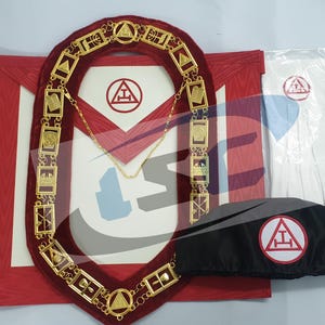May include: A Masonic regalia set featuring a gold-colored chain collar, a red apron with a white emblem, white gloves, and a black cap with a red and white emblem. The set is designed for ceremonial use.