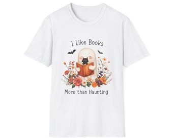 Op de afbeelding: Wit t-shirt met een afbeelding van een spook dat een boek leest, omringd door bloemen en vleermuizen. De tekst luidt "I Like Books More than Haunting."