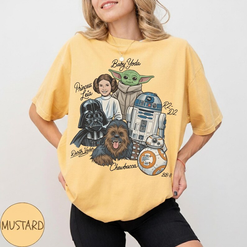 May include: Mustard yellow t-shirt with a graphic of Star Wars characters: Darth Vader, Princess Leia, Baby Yoda, Chewbacca, R2-D2, and BB-8. The word "Mustard" is in a circle at the bottom left of the shirt.