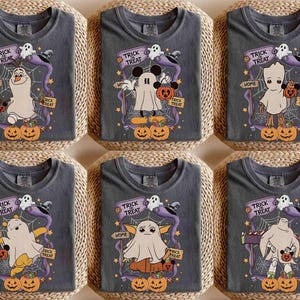 May include: Six gray t-shirts with Halloween-themed designs. Each shirt features a cartoon character dressed as a ghost, holding a pumpkin, with the words "Trick or Treat". The designs include Olaf, Mickey Mouse, Groot, Pikachu, Baby Yoda, and a generic ghost.
