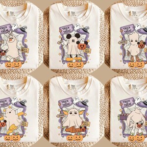 May include: Off-white t-shirts with Halloween-themed designs. Each shirt features a cartoon character dressed as a ghost, with pumpkins, a "Trick or Treat" banner, and the word "Home".