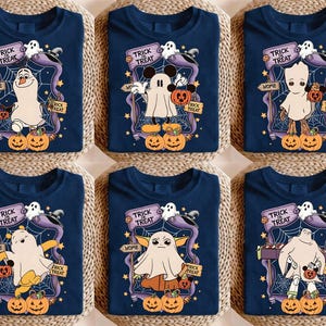 May include: Navy blue Halloween-themed t-shirts featuring various cartoon characters dressed as ghosts. Each shirt has a "Trick or Treat" sign, pumpkins, and a spiderweb design. The characters include Olaf, Mickey Mouse, and Baby Groot.