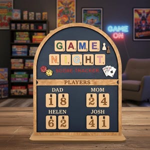 Könnte beinhalten: Holz-Spielabend-Score-Tracker mit den Worten "GAME NIGHT SCORE TRACKER" oben. Der Score-Tracker hat Platz für vier Spieler mit den Namen "DAD", "MOM", "HELEN" und "JOSH". Die Ergebnisse werden unter jedem Namen angezeigt. Würfel und Spielkarten sind ebenfalls abgebildet.