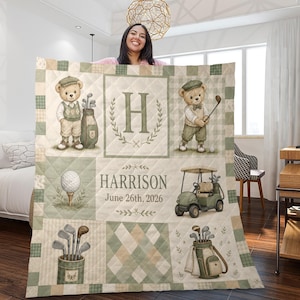 May include: A quilted blanket featuring a golf theme with illustrations of teddy bears in golf attire, golf clubs, a golf ball, and a golf cart. The design includes the letter H, the name Harrison, and the date June 26th, 2026, in a sage green and cream color palette.