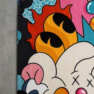 May include: A colorful, abstract rug with a cartoonish design. The rug features a variety of shapes and colors, including black, orange, pink, blue, and white. The design includes flame-like shapes, a cloud-like figure with crossed-out eyes, and other playful elements.