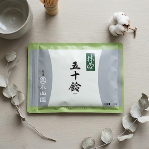 May include: A rectangular green and white pouch of Marukyu Koyamaen Isuzu matcha powder. The packaging features black Japanese kanji characters, the word ISUZU, and the text 100g. The design includes grey side panels and green borders.