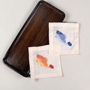 May include: A dark brown rectangular wooden tray with a raised edge. Two off-white square coasters with embroidered fish designs in red, orange, and blue are next to the tray. The fish are swimming.