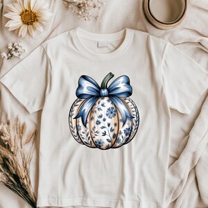 “Flat-lay of Pumpkin Season tee with coffee mug, blanket, and autumn decor.”