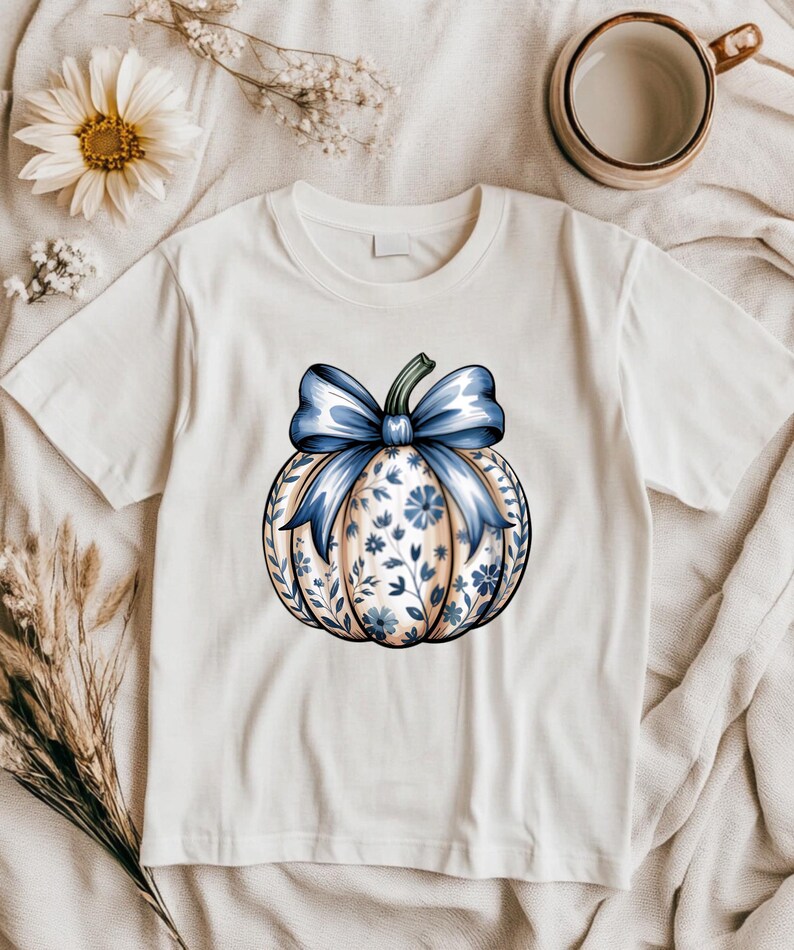 “Flat-lay of Pumpkin Season tee with coffee mug, blanket, and autumn decor.”