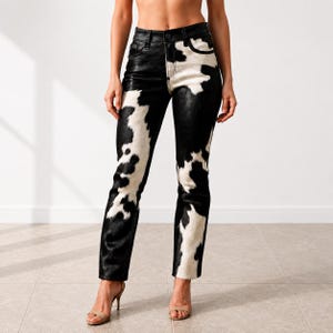 Puede incluir: Pantalones de corte recto con estampado de piel de vaca en blanco y negro. La cintura es de cuero negro con cierre de botón. El diseño de piel de vaca presenta parches irregulares en blanco y negro.