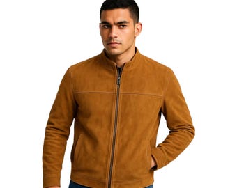May include: A tan suede jacket featuring a stand-up collar, a full-length center front zipper closure, and horizontal seam detailing across the chest. The jacket has long sleeves and two side pockets, providing a clean and structured appearance.