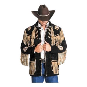 Può includere: Giacca in camoscio nera con frange beige e cuciture decorative. La giacca presenta un colletto a revers, chiusura con bottoni e toppe decorative sulle maniche. Un cappello da cowboy marrone completa il look.