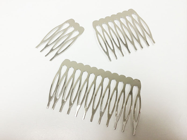 May include: Three silver-colored hair combs on a white background. The combs have a series of teeth and a curved design. The largest comb has 10 teeth, while the smaller combs have fewer.
