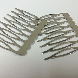 May include: Several silver-colored metal hair combs are arranged on a white surface. Each comb has a scalloped edge and multiple tines. The combs are designed to be inserted into the hair for decorative or functional purposes.