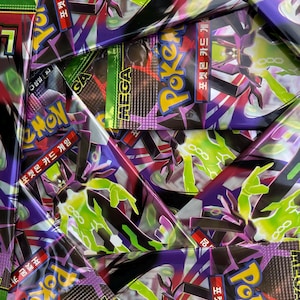 May include: A close-up shot of multiple Pokemon card packs. The packs are primarily purple, black, and green, with the word "MEGA" and Korean text visible. The packs feature various Pokemon characters and designs.