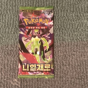 May include: A sealed Pokémon card pack with a green, purple, and black design. The pack features the word "MEGA" at the top and the Pokémon logo. The pack also has Korean text and an illustration of a green and black creature.