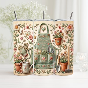 Peut inclure: Un gobelet sur le thème floral avec un motif de tablier de jardinier et le texte "Blooming with your love, Mom". Le motif comprend des outils de jardinage, des fleurs, des cœurs et des gants verts, roses et bruns. Le gobelet a une paille et un couvercle.