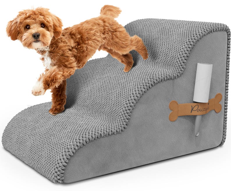 May include: A gray pet step with a textured, knitted top and smooth sides. A small, brown dog is stepping onto the top step. A bone-shaped tag with the word "Pawzy" is attached to the side, along with a lint roller.