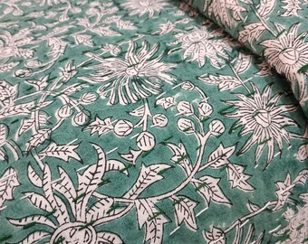 May include: A folded green and white floral patterned fabric. The design features large, stylized flowers and leaves in white against a teal green background. The fabric appears to be quilted or stitched.