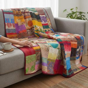 Peut inclure: Un couvre-lit patchwork multicolore composé de divers panneaux de tissu rectangulaires dans des tons de rouge, jaune, bleu, violet et orange. Le couvre-lit présente des surpiqûres kantha complexes et est bordé d'une bordure rouge foncé unie.