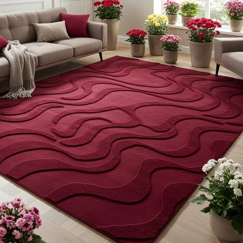 Puede incluir: Una alfombra rectangular grande de color burdeos con un patr&oacute;n de ondas en relieve. La alfombra es el punto focal de una sala de estar, con un sof&aacute;, sillas y plantas en macetas en el fondo. El dise&ntilde;o de la alfombra agrega textura e inter&eacute;s visual al espacio.