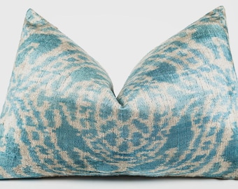 Può includere: Un cuscino decorativo con un motivo turchese e bianco sporco. Il cuscino ha un aspetto morbido e strutturato e una forma classica. Il design presenta un motivo astratto a vortice, che aggiunge un tocco di eleganza all'arredamento della casa.