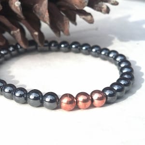 May include: A black and copper beaded bracelet. The bracelet is made of small, round beads. The beads are black for most of the bracelet, with a few copper beads at the end.