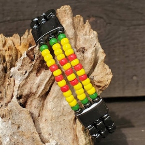 May include: A beaded bracelet with three rows of yellow, red, and green beads. The bracelet has a black metal clasp.