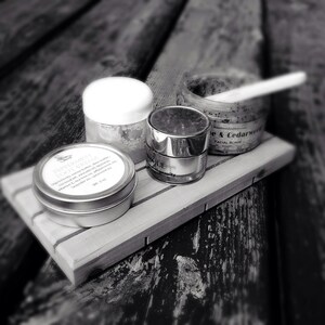 May include: A wooden tray with four small jars of skincare products. The jars are labeled "Peppermint Foot Cream", "Unique Gravity", "Handmade Cedarweed & Cedarwood Facial Scrub", and a fourth jar with an unreadable label.