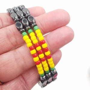 May include: Three beaded bracelets with a red, yellow, and green color scheme. The bracelets are made with small, round beads and have a magnetic clasp.