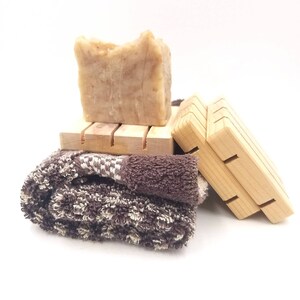 May include: A brown bar of soap on a wooden soap dish with a brown towel beside it.