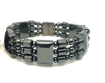 May include: A black hematite bracelet with three rows of beads and a magnetic clasp.