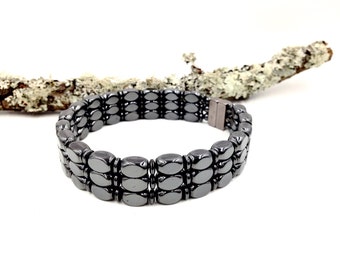 May include: A black hematite bracelet with three rows of oval-shaped beads and a magnetic clasp.