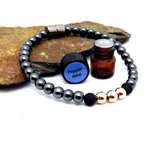 May include: A black hematite bracelet with a magnetic clasp, a small bottle of essential oil labeled "Peppermint", and lava rock and copper beads.