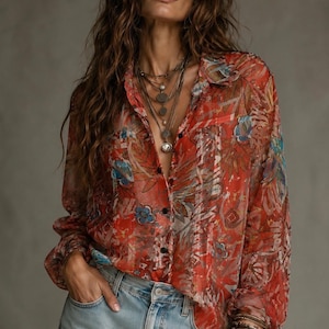 Peut inclure: Une chemise transparente à boutons avec un motif floral vibrant dans les tons de rouge, de bleu et de marron. Le chemisier à manches longues est associé à un jean en denim délavé. La chemise a un col et une poche sur la poitrine.