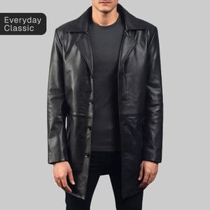 Puede incluir: Un abrigo de cuero negro con un diseño clásico. El abrigo tiene una parte delantera abotonada, un cuello con muescas y una longitud hasta la mitad del muslo. El texto "Everyday Classic" está en la esquina superior izquierda.