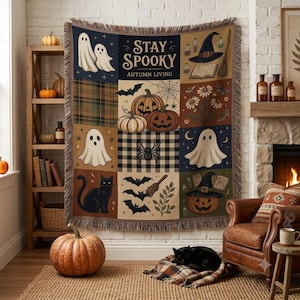Könnte beinhalten: Eine gewebte Wohndecke mit einem Raster aus Halloween-Motiven, darunter Geister, Kürbisse, eine schwarze Katze, Fledermäuse, eine Spinne und ein Hexenhut. Der Text "STAY SPOOKY" und "AUTUMN LIVING" ist in der Mitte des Designs aufgedruckt.