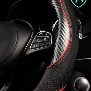 May include: Black and red steering wheel cover with carbon fiber accents. The cover has a perforated texture and red stitching. Text on the image reads "Your Car Deserves The Best" and "Lord Autofashion".