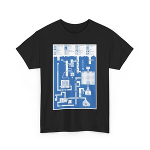 Peut inclure: T-shirt noir avec un motif de carte bleu et blanc. La carte présente un plan détaillé avec des zones étiquetées, une rose des vents indiquant le nord et des éléments architecturaux. Le t-shirt est à col rond.