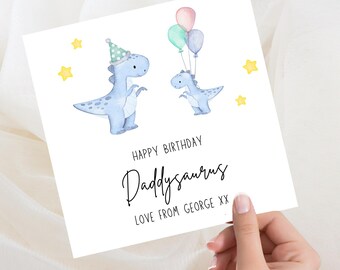 May include: A white greeting card with watercolor illustrations of two blue dinosaurs. One dinosaur wears a party hat, and the other holds balloons. The card reads "Happy Birthday Daddysaurus" and "Love from George XX."