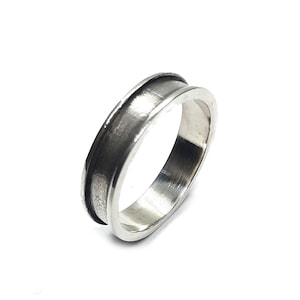 Puede incluir: Un anillo de banda de plata simple con un borde ligeramente elevado.