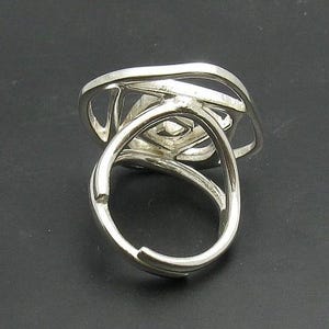 May include: A silver ring with a unique, abstract design. The ring is made of multiple intertwined bands that create a geometric pattern.